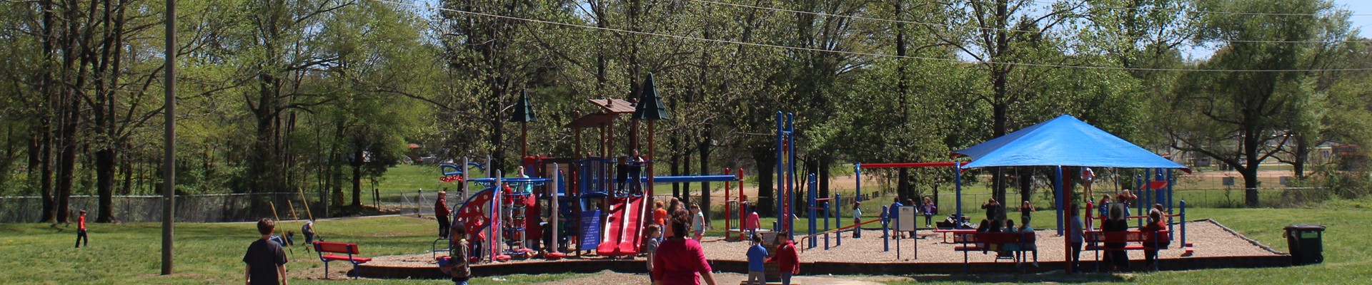 Students playing on playground equipment on a sunny day.
